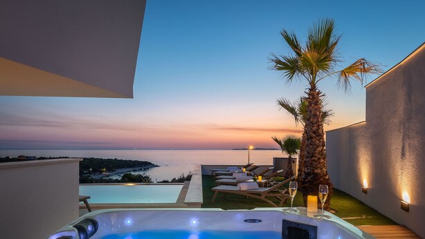 A hot tub with a sunset view, lounge chairs, and a palm tree. - Villa Rossa Zadarvillas (Primosten)
