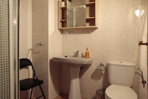 A bathroom with a pedestal sink, toilet, and a small mirror above the sink. - Apartamentos Irati Olaldea (Oroz Betelu)