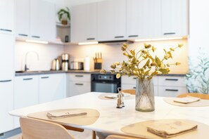 Eine moderne Küche mit weißen Schränken, einem Esstisch mit Platzsets und einer Vase mit Blumen.