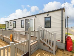 A mobile home with a front deck, a sliding door, and a gas cylinder. - Caravan A7 (Bridport)