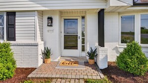 A white house with a front door, a 'hello' mat, and two potted plants. - Hot Tub Farm Home, Near Sight & Sound (Ronks)