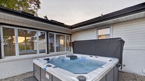 A hot tub in a covered outdoor area with a brick wall and windows. - Hot Tub Farm Home, Near Sight & Sound (Ronks)