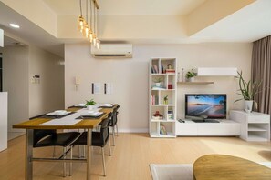 A modern living room with a dining area, a flat-screen TV, and a bookshelf. - Modern Luxe Stay-2BR City Escape (Taguig City)