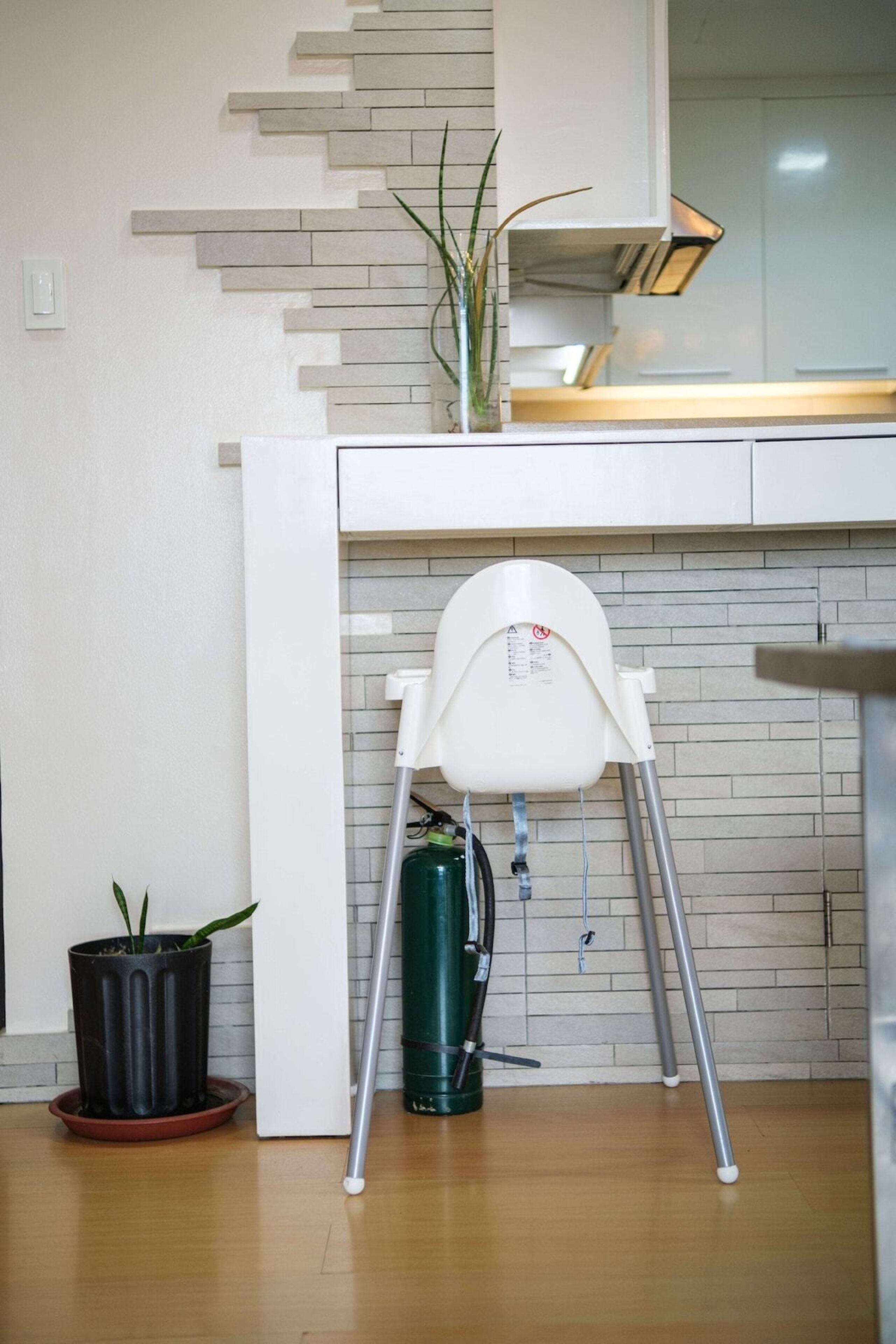 A kitchen with a white chair, a green water dispenser, and a potted plant.