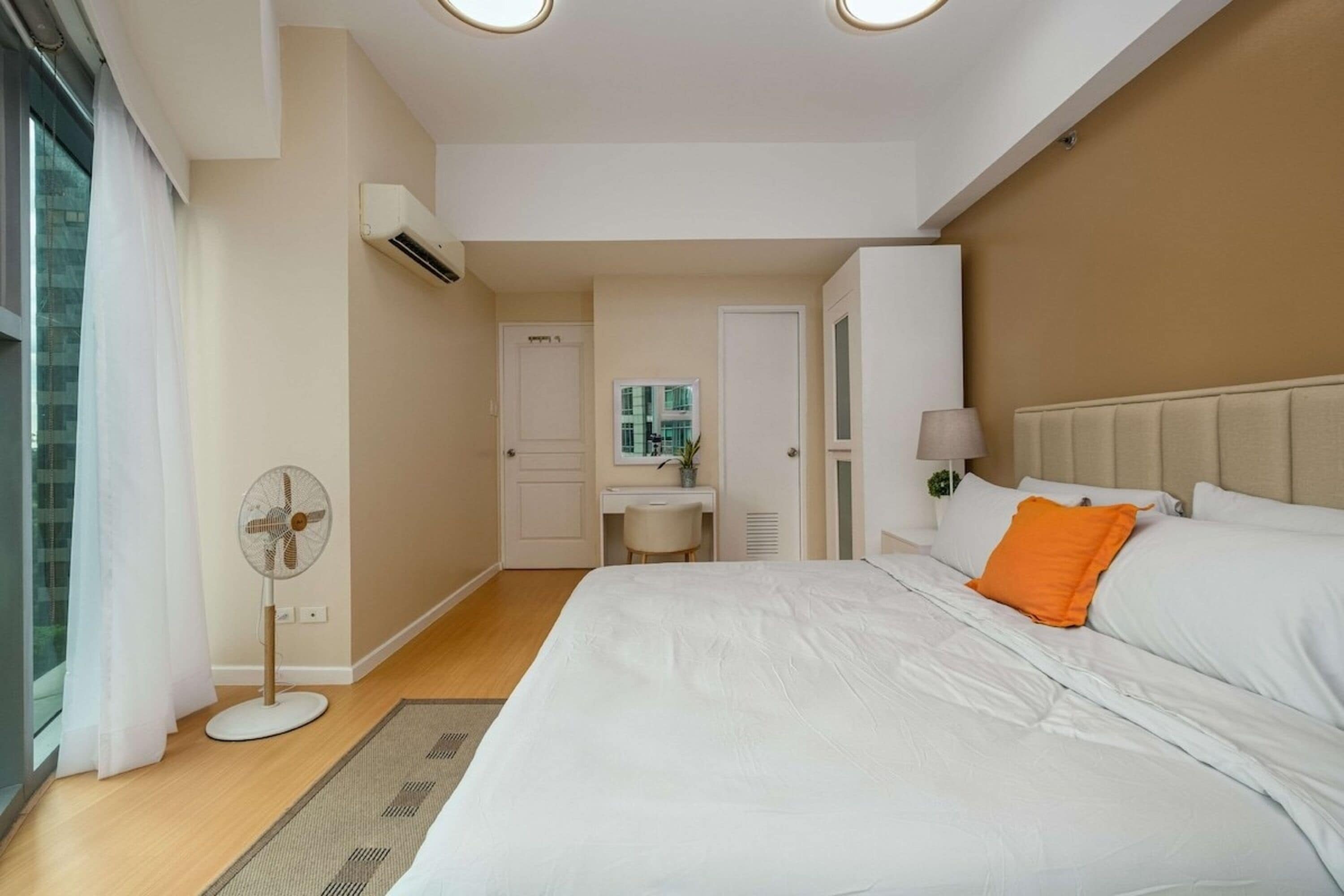 Ein Hotelzimmer mit Bett, Nachttisch, Lampe und Klimaanlage.