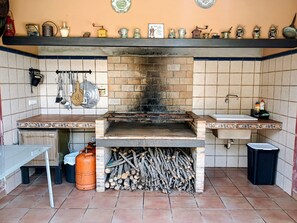 Une cuisine Ă©quipĂ©e dâun four Ă briques, de murs carrelĂ©s, dâun Ă©vier et de divers ustensiles de cuisine.