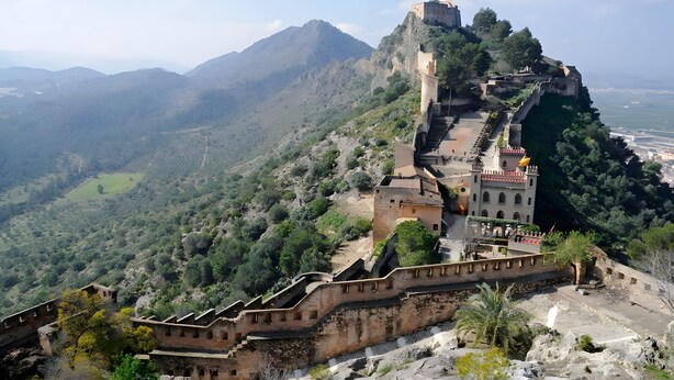A historic fortress with a prominent tower, a fortified wall, and a view of the surrounding landscape. - Holiday Home 'Cova Negra Nature' with Mountain Views, Shared Pool, and Air Conditioning (El Genovés)