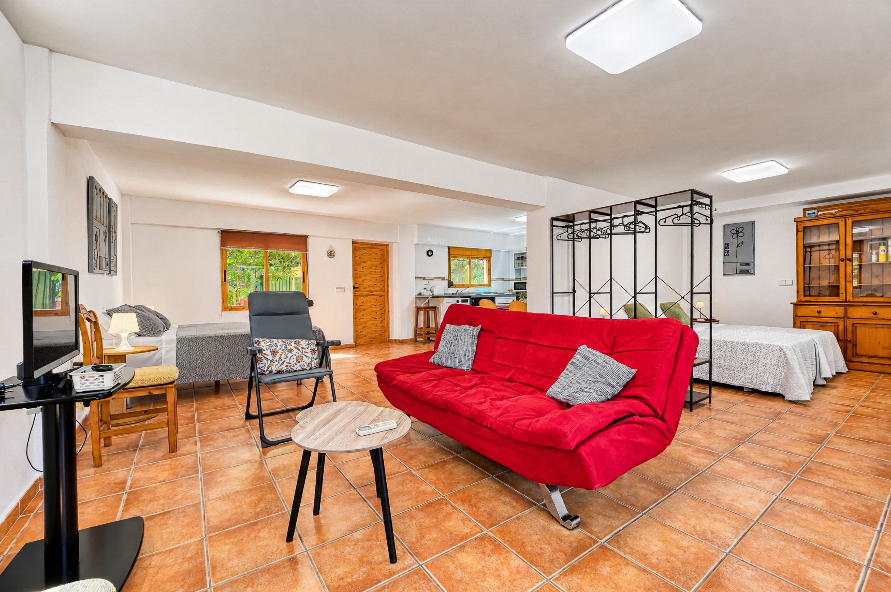 Una sala de estar con un sofá rojo, una televisión y un comedor con mesa y sillas.