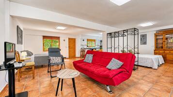 Una sala de estar con un sofá rojo, una televisión y un comedor con mesa y sillas.