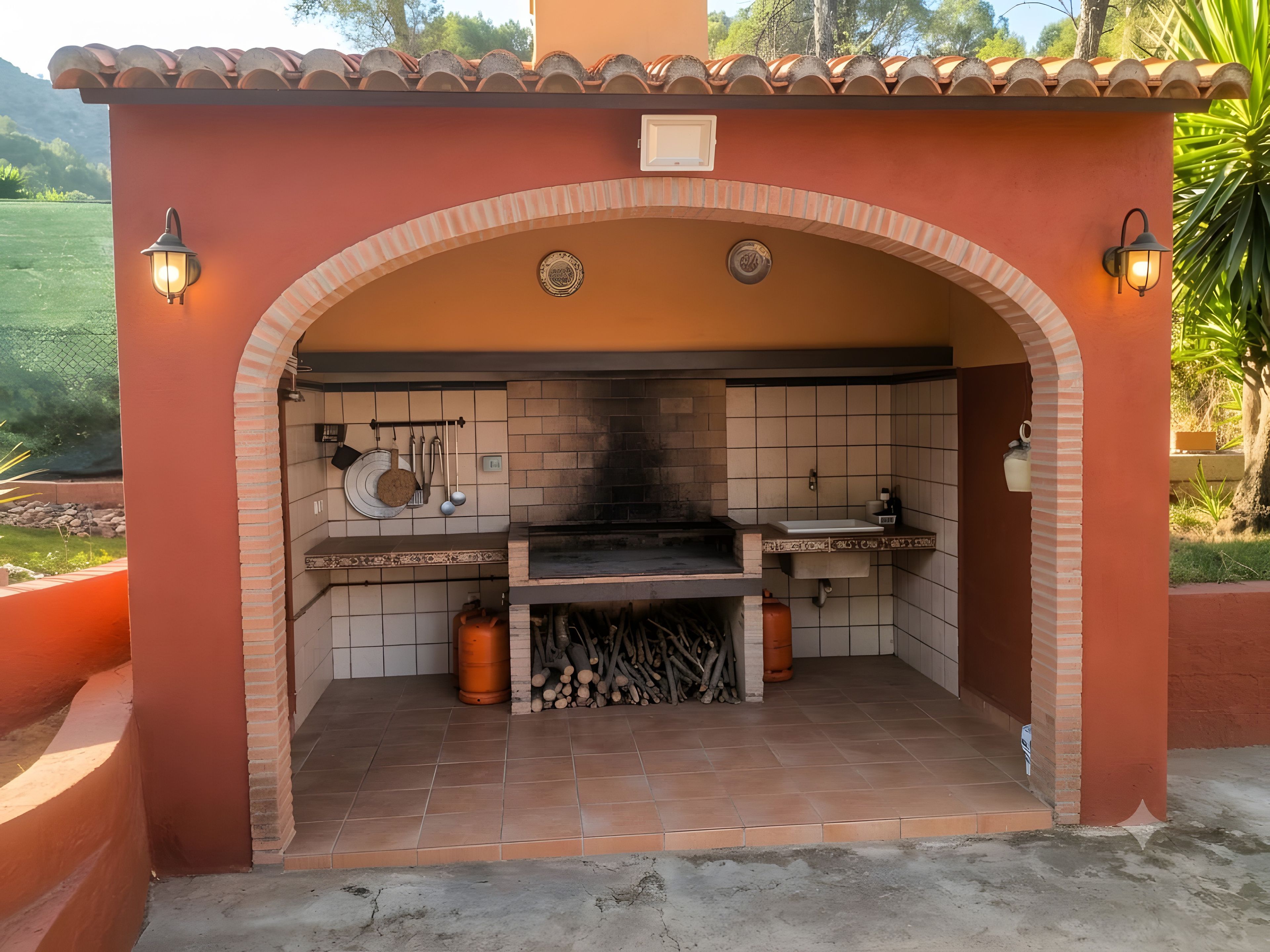 Una cocina exterior con un arco de ladrillo, un horno de leña y un fregadero.