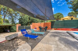 Un espace extérieur aménagé avec une piscine, des chaises longues et un coin salon abrité.