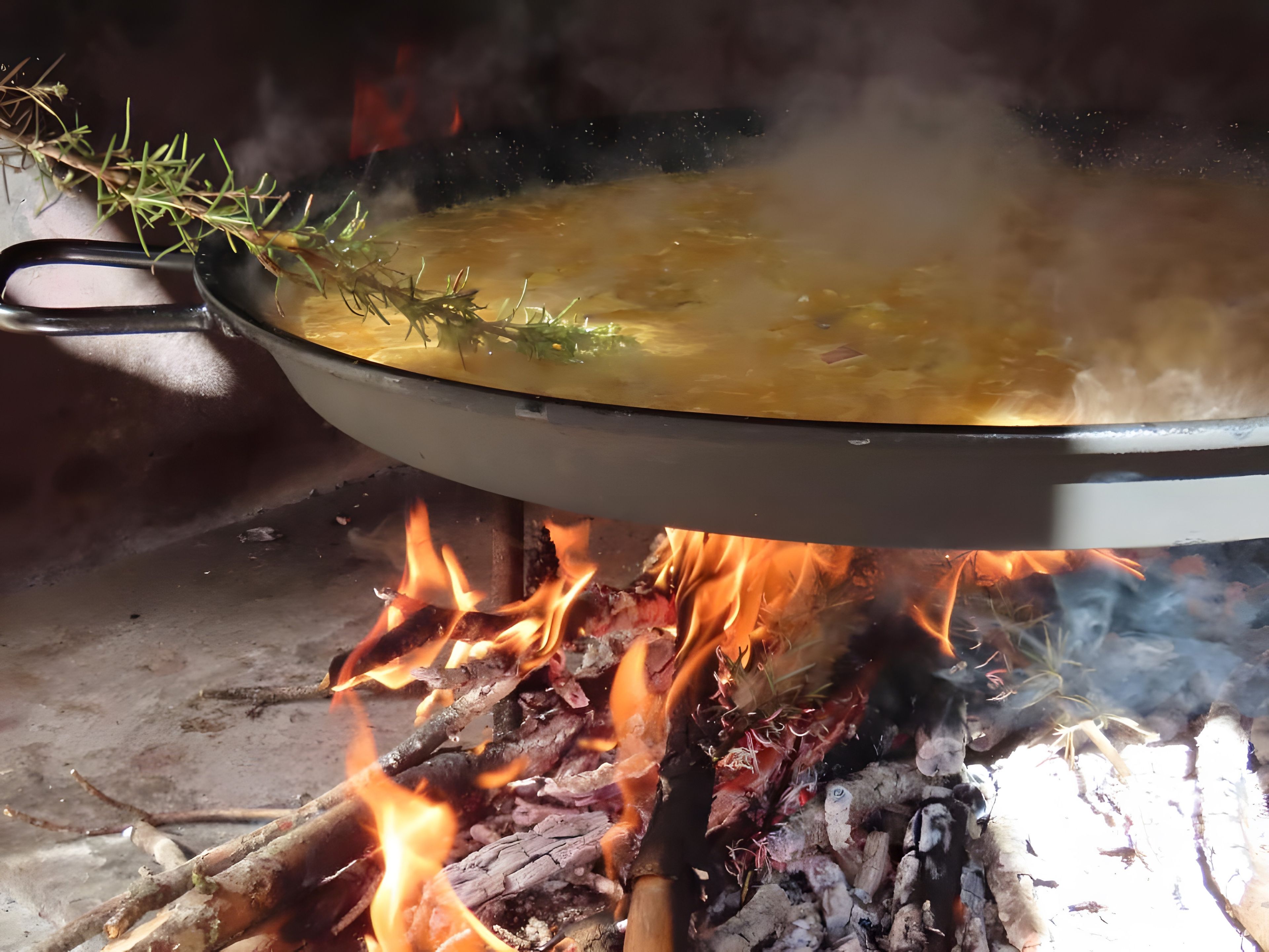Una olla sobre fuego abierto con llamas debajo.