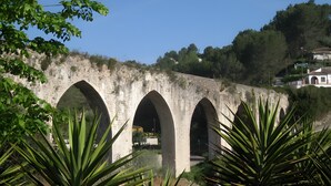 A stone bridge with multiple arches, surrounded by greenery and a hillside in the background. - Holiday Home 'Cova Negra Nature' with Mountain Views, Shared Pool, and Air Conditioning (El Genovés)