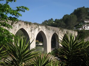 A stone bridge with multiple arches, surrounded by greenery and a hillside in the background. - Holiday Home 'Cova Negra Nature' with Mountain Views, Shared Pool, and Air Conditioning (El Genovés)