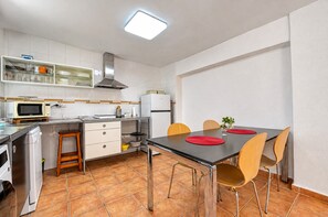 A compact kitchen with white cabinets, a microwave, a stove, and a dining table with chairs.