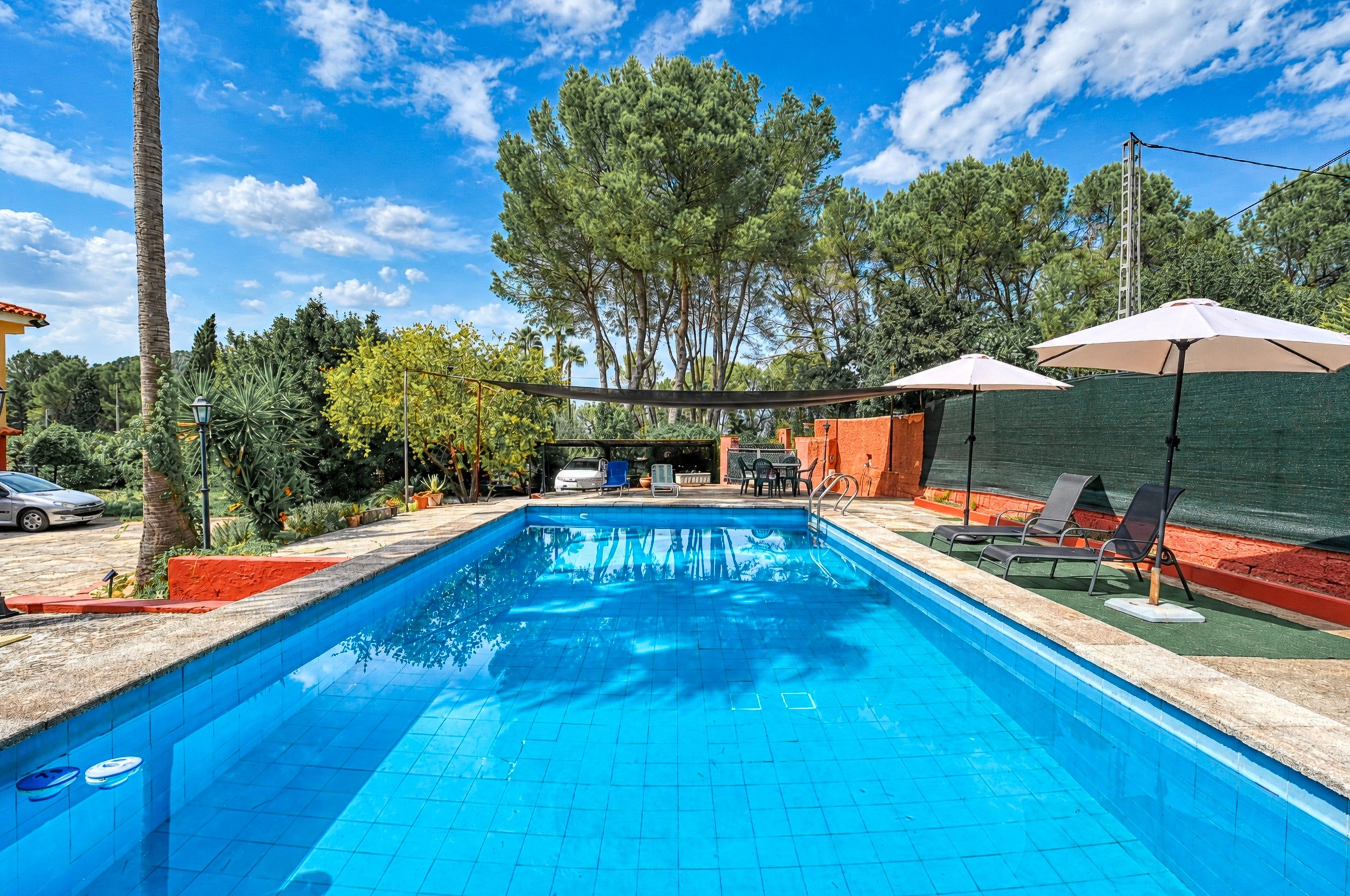 Una piscina rectangular con agua azul cristalina, rodeada por un solárium empinado.