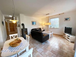 Ein Wohnzimmer mit einer Couch, einem Couchtisch, einem Fernseher und einem Kamin.