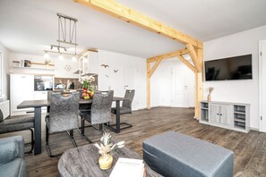Eine moderne Küche mit Essbereich, Holzbalken, einem Flachbildfernseher und einem Esstisch mit Stühlen.