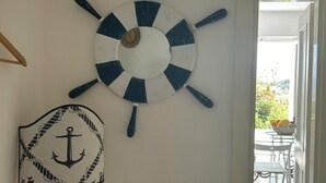 En vägg med en väggdekoration i marint tema, ett litet bord med en lampa och utsikt över en uteplats.