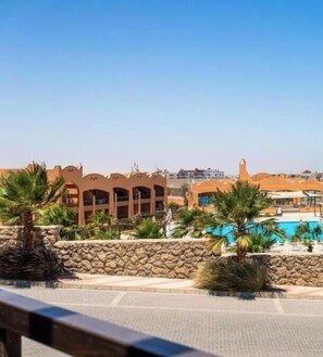Ein Hotel mit Pool, Palmen und einer Steinmauer.