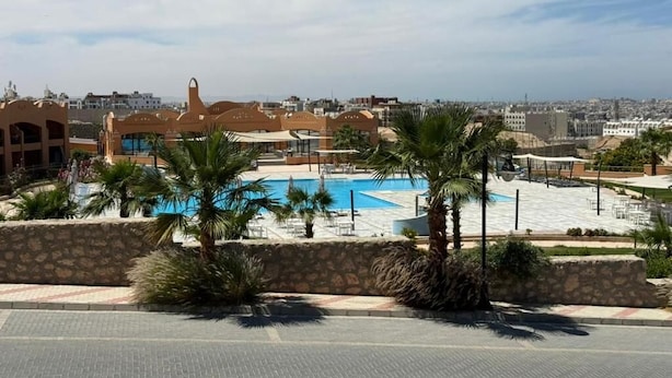Ett semesterhotell med en swimmingpool, palmer och utsikt över stadsbilden.