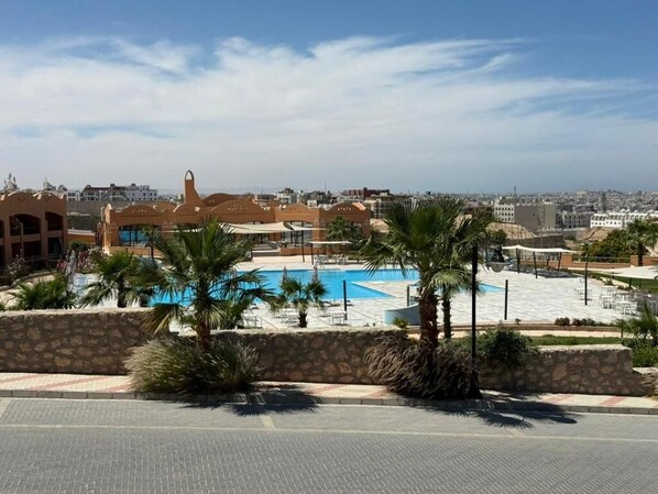 Ein Resort mit Swimmingpool, Palmen und Blick auf die Stadtlandschaft.