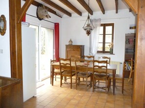 Un comedor con una mesa y sillas de madera, un candelabro, una ventana con cortinas y una estantería.