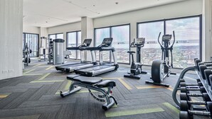 Une salle de sport équipée de tapis de course, de vélos elliptiques et de bancs de musculation.
