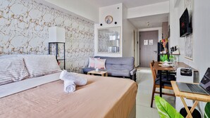 Une chambre d’hôtel comprenant un lit, un bureau avec un ordinateur portable, un canapé, une table à manger et un téléviseur.