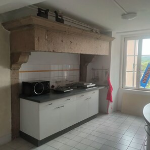 A kitchen with white cabinets, a black countertop, a microwave, and a stove.