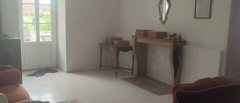 A living room with a fireplace, a mirror, and a door leading to a balcony.