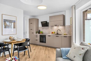 Una cuina moderna amb zona de menjador, forn de mur i finestra amb vista a la ciutat.