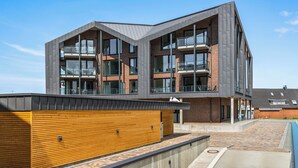 A modern multi-story building with large windows and balconies. - The View A04 Cloudsurfer  – Balcony, Garden Furniture, Shared Sauna, Parking (Dagebüll)