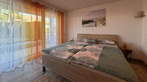 A bedroom with a bed, a nightstand, a wall-mounted lamp, a painting, and a sliding glass door leading to an outdoor area. - Time out by the lake: Luxurious vacation apartment with garden (Gaienhofen)