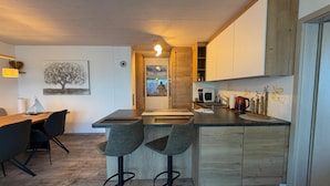 A modern kitchen with a central island, bar stools, and a dining area with a table and chairs. - Time out by the lake: Luxurious vacation apartment with garden (Gaienhofen)
