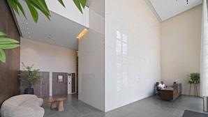 Un área de recepción moderna con un mostrador, asientos y una pared grande con un diseño geométrico.