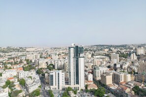 A high-rise building with a modern design, surrounded by a densely populated urban area with various other buildings. - La rose de savion- downtown, jerusalem Mamad (Jerusalem)