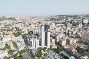 An aerial view of a cityscape with a prominent modern high-rise building in the center, surrounded by a mix of residential and commercial buildings. - La rose de savion- downtown, jerusalem Mamad (Jerusalem)