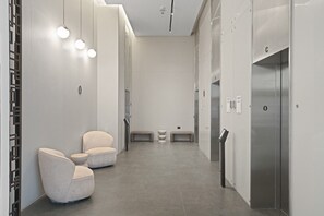 A modern elevator with a metallic finish, a waiting area with two cushioned chairs, and a clean, minimalist design. - La rose de savion- downtown, jerusalem Mamad (Jerusalem)