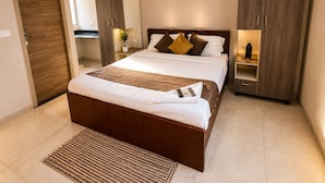 A modern bedroom with a large bed, a bedside table, a wardrobe, and a mirror.