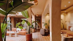 A spacious lobby with a patterned floor, comfortable seating, and various potted plants. - Maison Nalos (Marrakech)