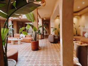 A spacious lobby with a patterned floor, comfortable seating, and various potted plants.