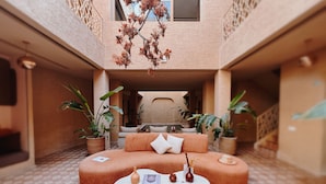 A modern interior with a sofa, coffee table, and potted plants. - Maison Nalos (Marrakech)