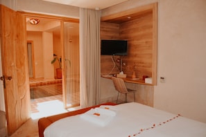 Ein Hotelzimmer mit einem Bett, einem Schreibtisch, einem Fernseher und einer Schiebetür zu einem Badezimmer.