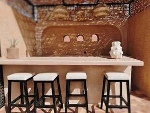 A bar area with a counter and three stools. - Maison Nalos (Marrakech)