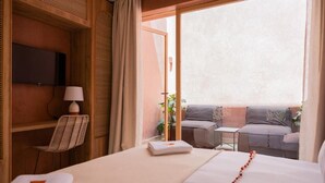 A hotel room with a bed, a chair, a small table, a TV, and a balcony with seating. - Maison Nalos (Marrakech)