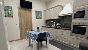 Cocina compacta con una mesa de comedor, un sofá y un televisor montado en la pared.