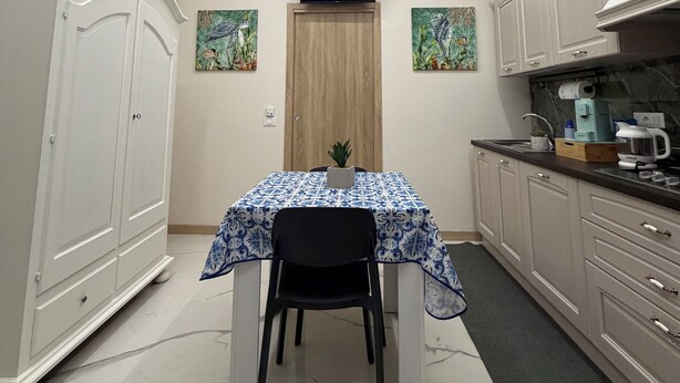 Cocina compacta con una mesa de comedor, un televisor sobre la puerta y una planta en maceta sobre la mesa.