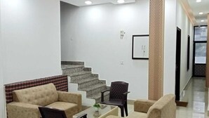 A modern living room with a sofa set, a coffee table, and a chair. There is a staircase leading to another level. - Hotel Paul Residency  (Malout)