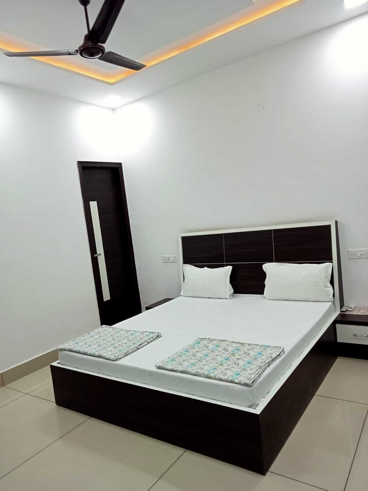 A bedroom with a bed, bedside tables, a ceiling fan, and a door.